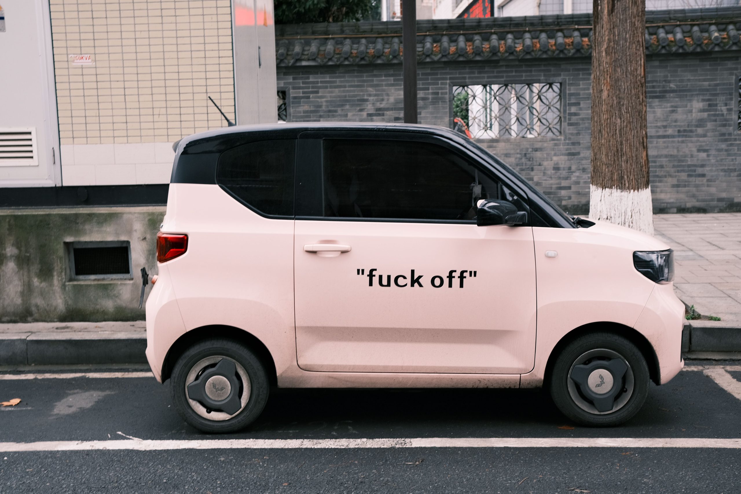 Reva électrique rose garée dans une rue urbaine