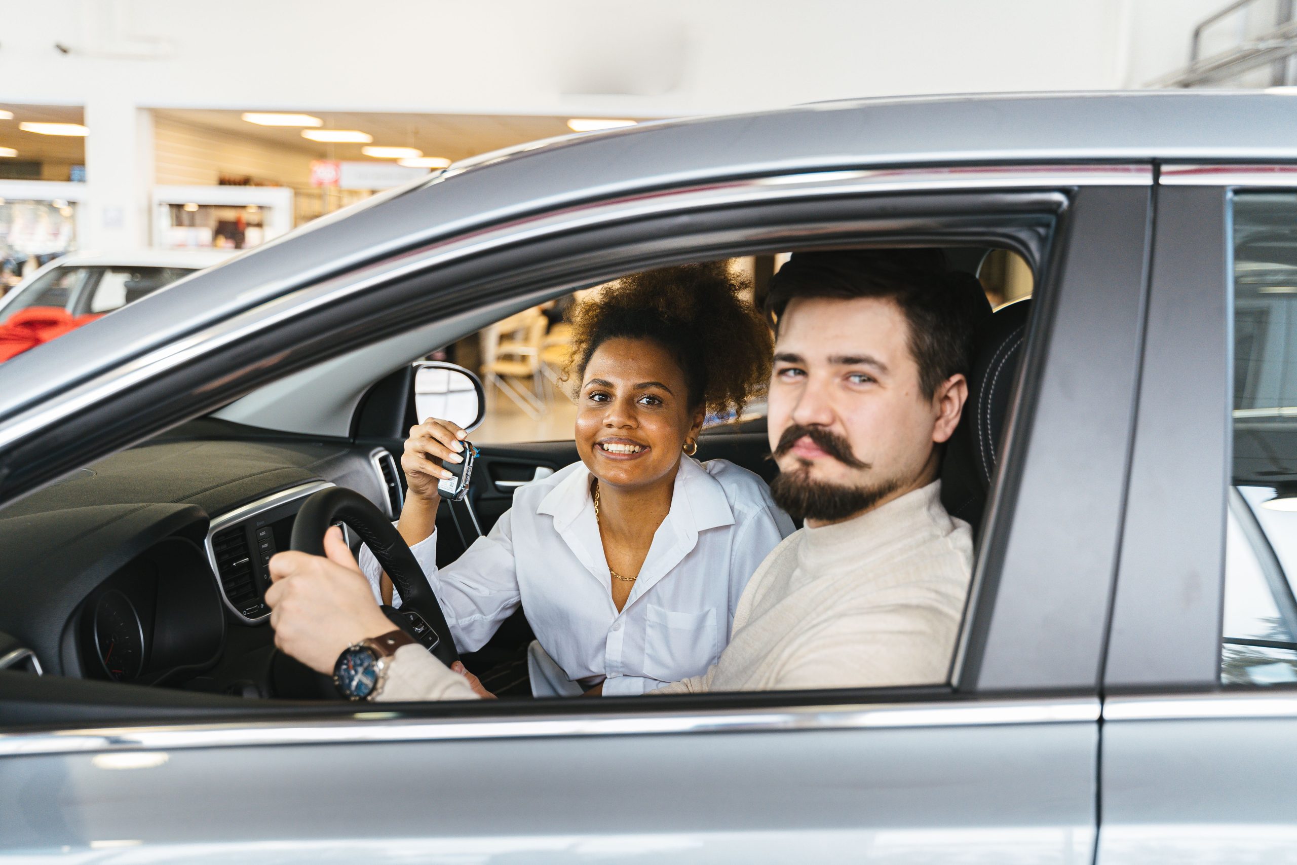 Couple souriant dans nouvelle voiture tenant clé satisfait