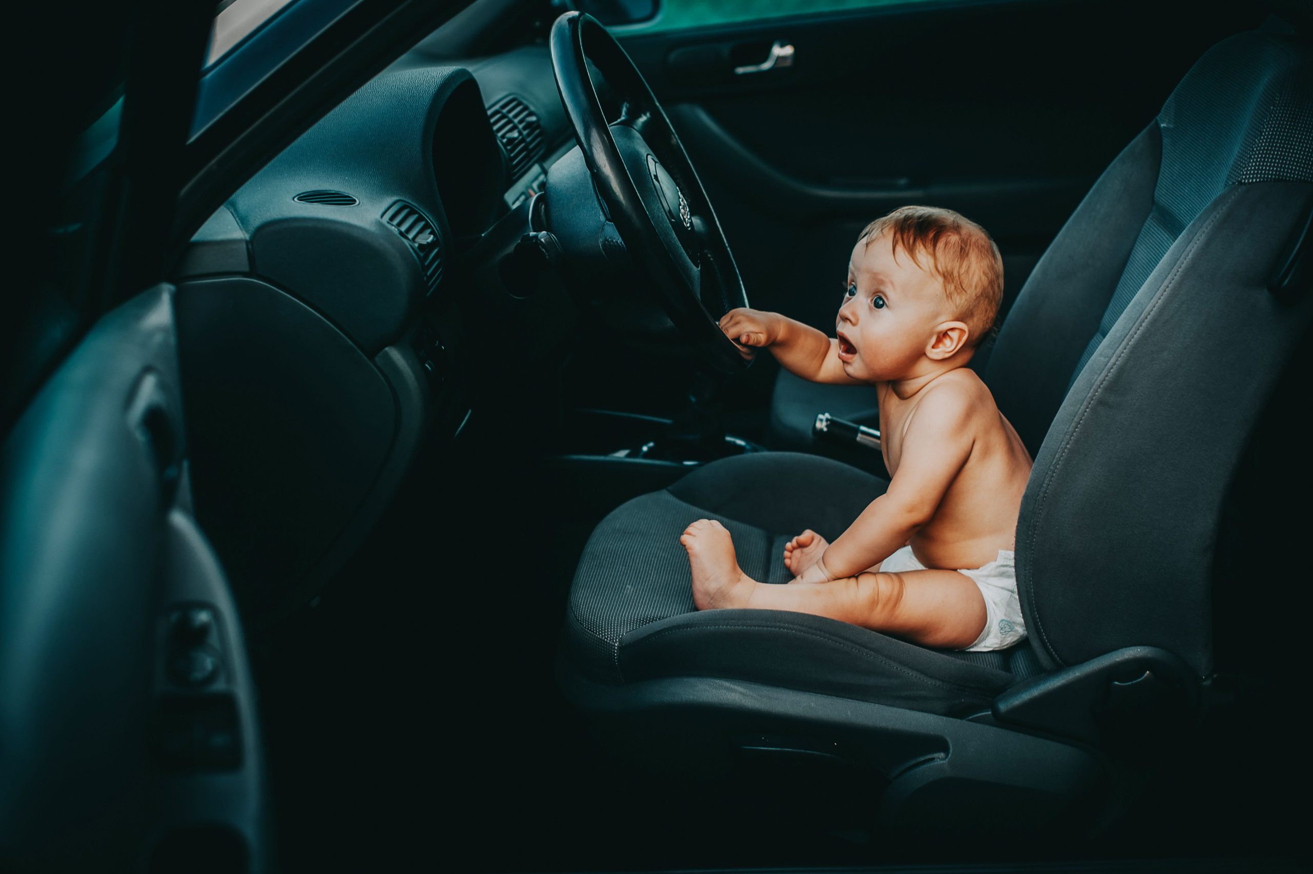 Bébé curieux assis au volant d'une voiture
