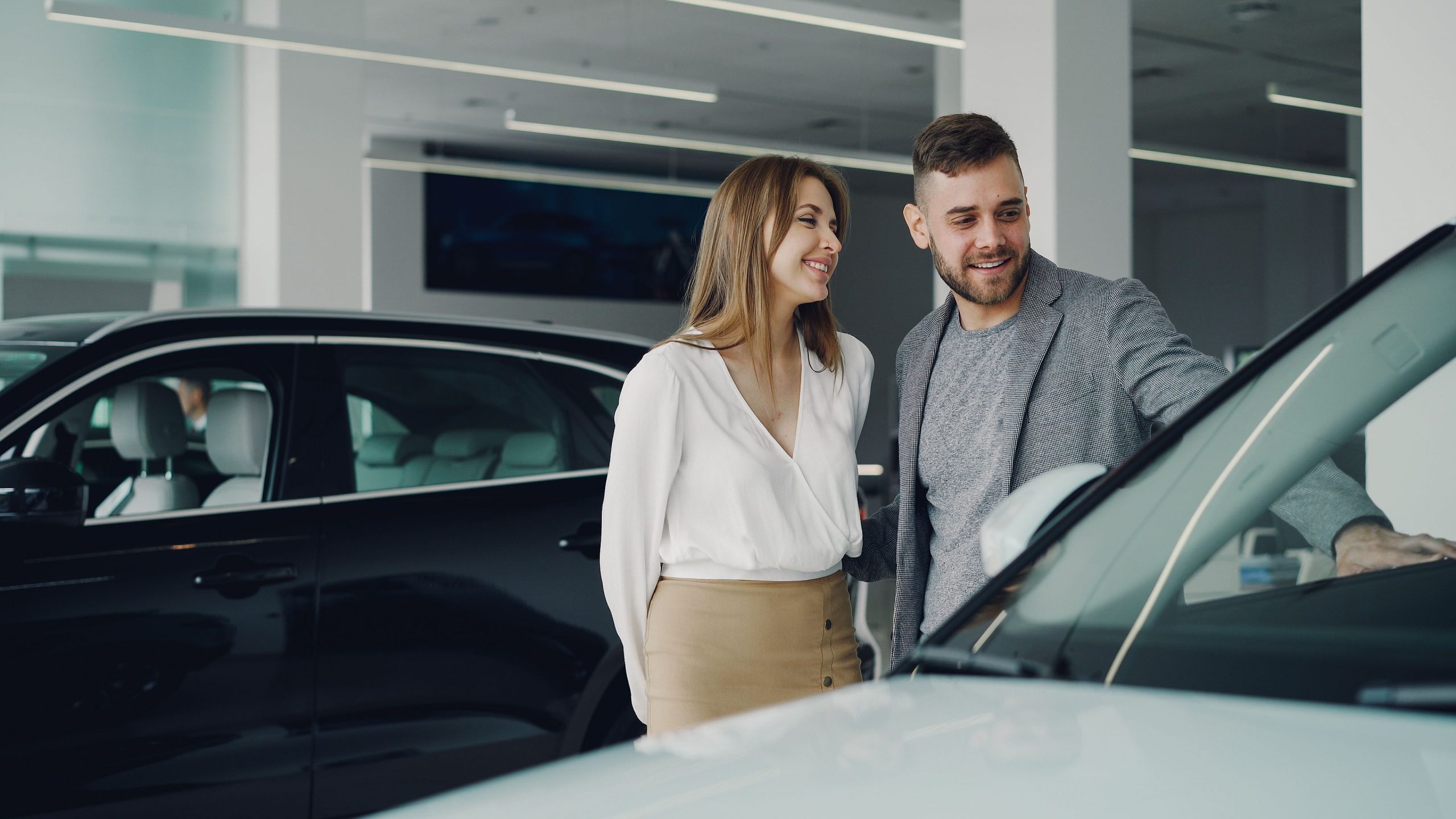 Couple souriant explorant voitures chez concessionnaire