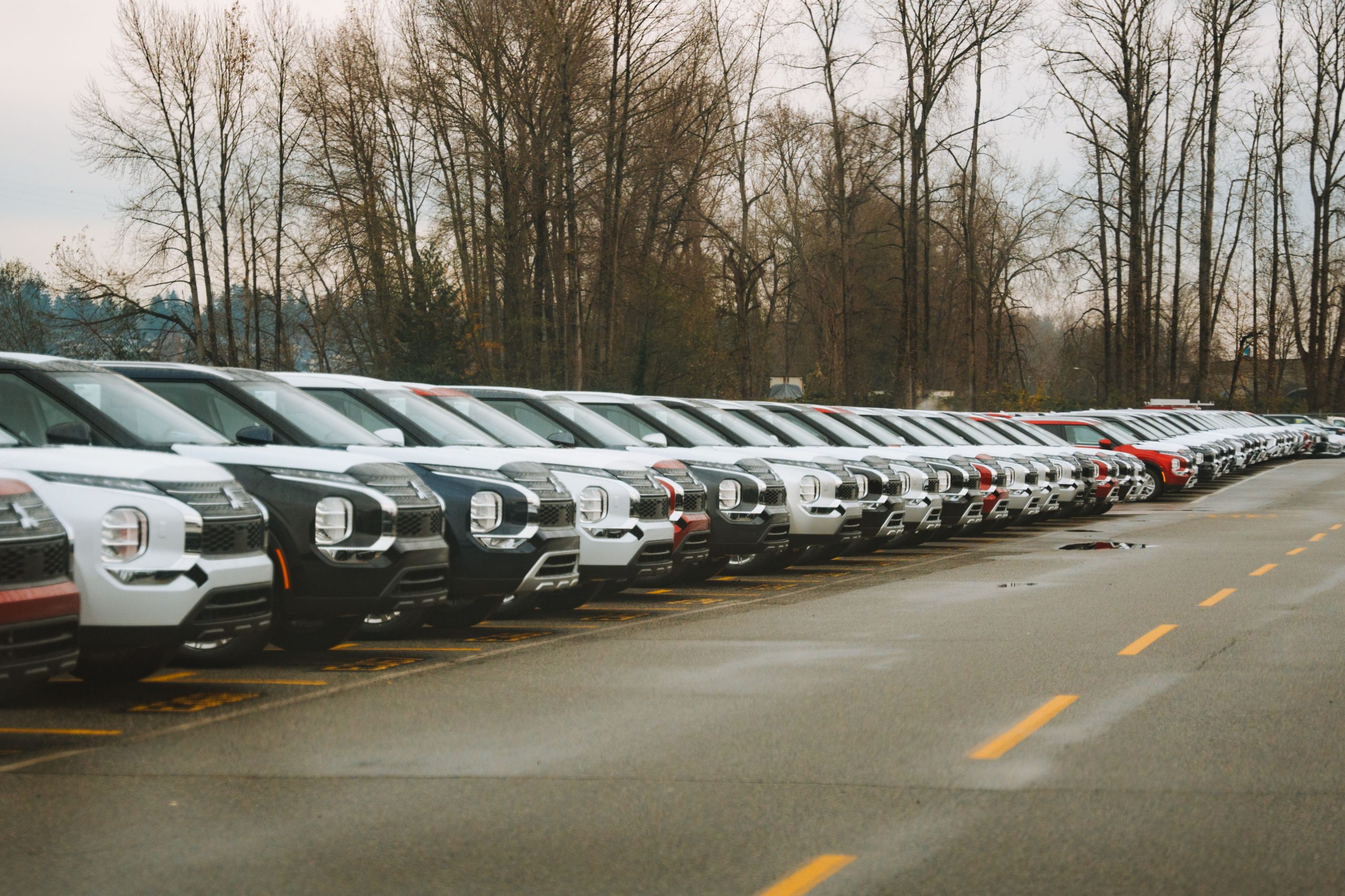 Rangée de nouveaux SUV dans un parking extérieur.